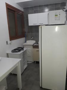 a small kitchen with a white refrigerator and cabinets at Apto Jk em Cachoeirinha in Cachoeirinha +4 photos