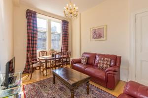 sala de estar con sofá de cuero y mesa en Menzies Apartments, en Edimburgo