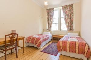 1 dormitorio con 2 camas, escritorio y ventana en Menzies Apartments, en Edimburgo