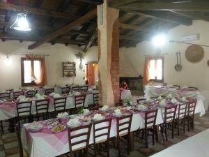 un groupe de tables dans une pièce avec des réglages de table roses dans l'établissement Agriturismo S´Aranada, à Marrùbiu