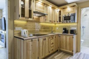 a kitchen with wooden cabinets and a sink and a microwave at Polana Szymoszkowa Ski Resort in Zakopane