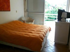 a bed with an orange comforter in a bedroom at Casa em condomínio fechado de frente para o mar e ao lado do rio in Praia Guaratuba