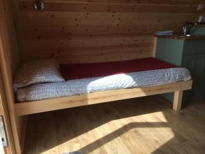 a bed in a room with a wooden wall at Acheninver Hostel in Achiltibuie