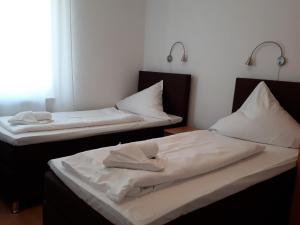 2 łóżka w pokoju z białą pościelą i poduszkami w obiekcie Hotel Taverne Inos w Hanowerze