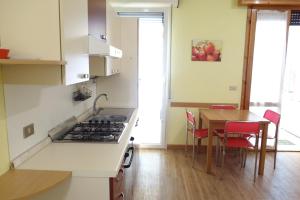 een keuken met een fornuis en een tafel met stoelen bij Appartamento Holiday Rimini 100mt dal mare in Rimini