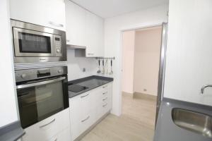 een keuken met witte kasten en een roestvrijstalen apparaat bij Apartamento Playa Fontanilla in Marbella