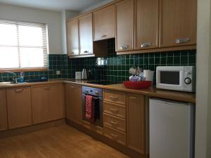 インバネスにあるTwo-Bedroom Apartment - Golf View Free Parkingのキッチン(木製キャビネット、白い電子レンジ付)