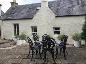 um grupo de cadeiras e uma mesa em frente a uma casa em Three-Bedroom Old Cottage Free Parking em Inverness