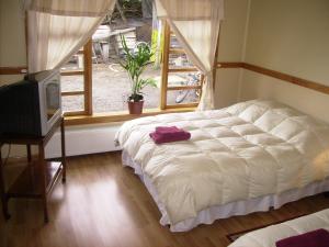 um quarto com uma cama branca e uma janela em Hostal El Rincón em Puerto Natales