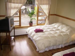 um quarto com uma cama branca e uma janela em Hostal El Rincón em Puerto Natales