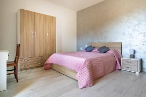 um quarto com uma cama rosa e armários de madeira em Villa Russo em Vico Equense