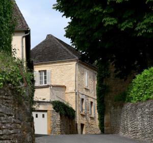 an old stone house with a white garage at MAISON DE MARQUAY-MAISON D'HOTES in Marquay