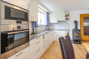 a kitchen with white cabinets and a stove top oven at Ferienwohnung Metzler - Blick auf die Berge in Göfis