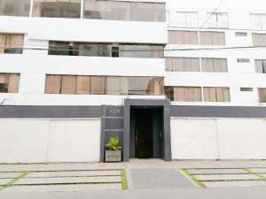 un edificio blanco con una puerta negra y una planta en Departamento Monterrico, en Lima