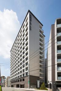 a tall white building on the corner of a street at Shizutetsu Hotel Prezio Hakataekimae in Fukuoka