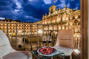 un tavolo con un piatto di cibo e bicchieri di vino di Salamanca Luxury Plaza a Salamanca