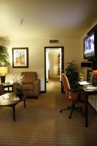 a lobby with a living room with a couch and a television at Ramada by Wyndham Viscount Suites Tucson East in Tucson