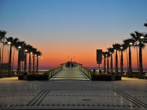 a boardwalk with palm trees on the beach at sunset at Hotel Regina in Lido di Camaiore