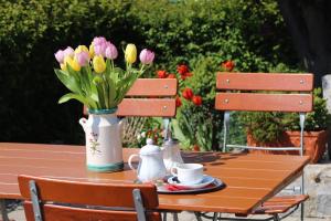 een houten tafel met een vaas van roze en gele bloemen bij Hotel Hecht Garni in Ingolstadt