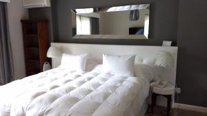a white bed in a bedroom with a mirror at Apartamento Forest Lagoon Punta Del Este in Punta del Este