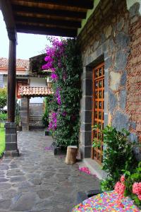 a stone building with flowers and a wooden door at Casa del siglo XVII in Jocotitlán