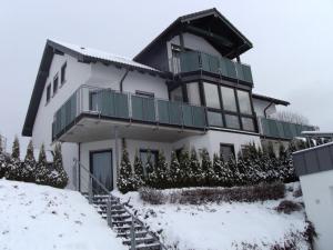 a large white house with a balcony in the snow at Ferienwohnung Moos-Hochsauerland in Wiemeringhausen