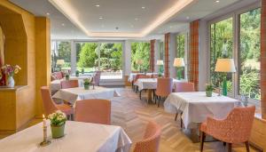 un restaurante con mesas, sillas y ventanas en Hotel Thomahof, en Hinterzarten