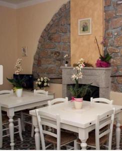 un restaurant avec des tables et des chaises blanches et une cheminée dans l'établissement Guest House Le Gemelle, à Luras