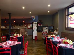 a restaurant with tables with red chairs and a refrigerator at Hostal Esquina Patagónica in Coihaique
