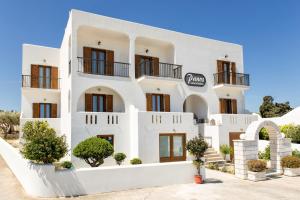 a white building with balconies and trees in front of it at Panos Luxury Studios in Parikia