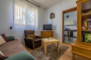 a living room with a couch and a chair and a table at Apartman Laura in Selce