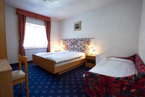 a hotel room with two beds and a window at Hotel Garnì Nès Crépes in Pozza di Fassa