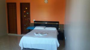 a bedroom with a white bed with an orange wall at Casa em Arraial / Monte Alto in Arraial do Cabo