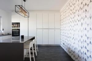 a kitchen with white cabinets and a counter with stools at Volcanic Charming House in Ribeira Grande