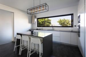 a kitchen with white cabinets and a large window at Volcanic Charming House in Ribeira Grande