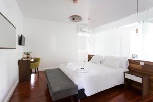 a white bedroom with a white bed and a table at Volcanic Charming House in Ribeira Grande