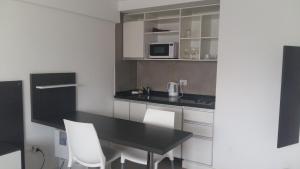 cocina con mesa negra y sillas blancas en Rosario Paladium Apartment en Rosario