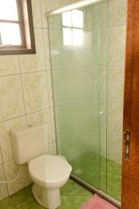 a bathroom with a toilet and a glass shower at Chalé saí azul in Penedo