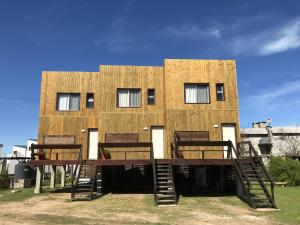 un edificio con 4 sillas de madera delante en Ammunaini en Punta Del Diablo