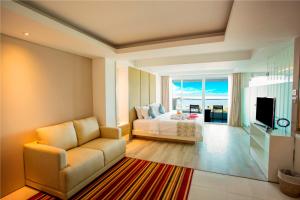 ヌサドゥアにあるBenoa Sea Suites and Villasのベッドルーム(ベッド1台、ソファ、テレビ付)