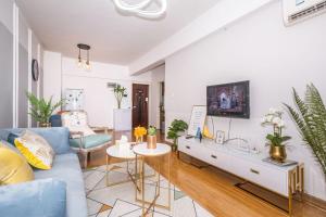 sala de estar con sofá azul y TV en Zhengzhou Jinshui·Manhattan Commercial Plaza· Locals Apartment 00163340, en Zhengzhou