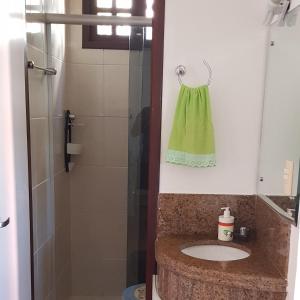 a bathroom with a sink and a shower with a green towel at Paraiso de Maracajau 1 in Maracajaú