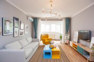 a living room with a white couch and a tv at Zhengzhou Zhongyuan·Zhongyuan Wanda· Locals Apartment 00122680 in Zhengzhou