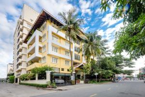 a yellow and white building on a street with palm trees at City View Apartment in Phnom Penh