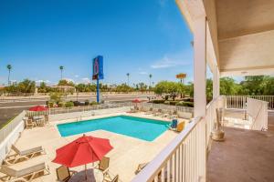 una piscina con sillas y sombrillas en el balcón en Motel 6-Youngtown, AZ - Phoenix - Sun City, en Youngtown
