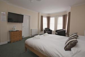 a bedroom with a bed with two chairs and a flat screen tv at All Seasons Lodge Hotel in Great Yarmouth
