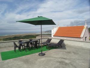 カルバージョにあるA casa de Chucoの屋根に緑の傘を置いたテーブルと椅子