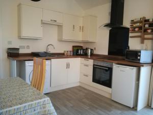 una cucina con armadi bianchi, lavandino e forno a microonde di Riverside Cottage a Carrickfergus