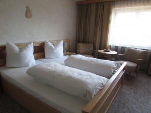 a hotel room with a bed with white sheets and pillows at Ferienhaus Tschenett in Imst