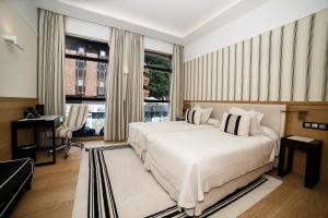 a bedroom with a large white bed and a desk at Gran Hotel Sardinero in Santander